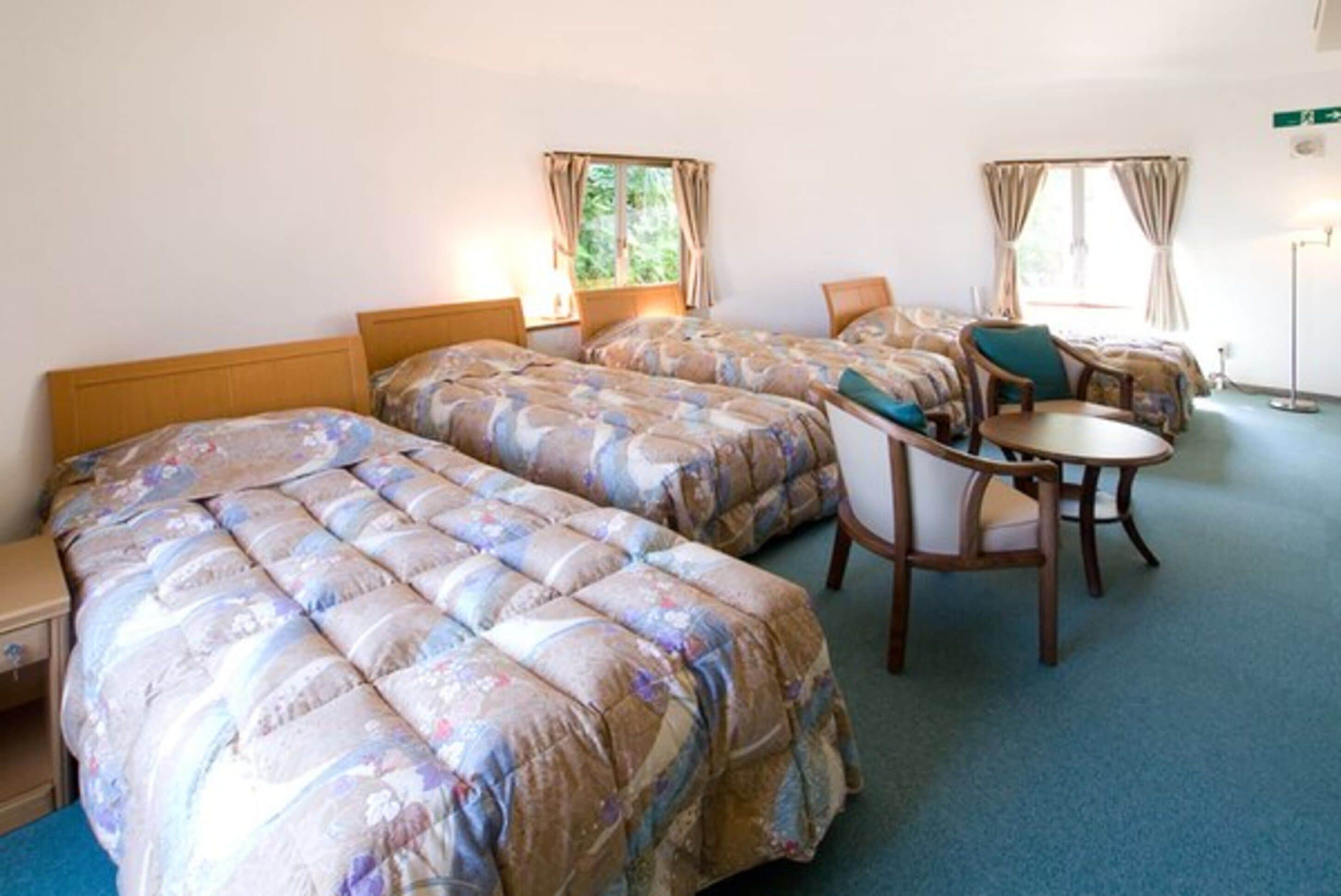 Ett hotellrum med två sängar, ett litet bord och en stol.