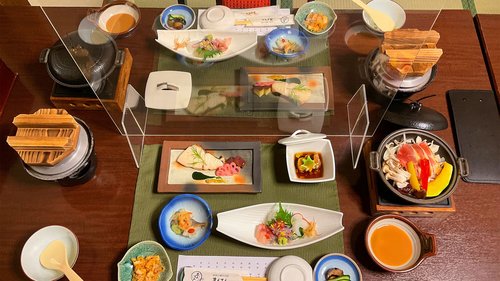 A dining table with various dishes and condiments, including sushi, sashimi, and a variety of side dishes.