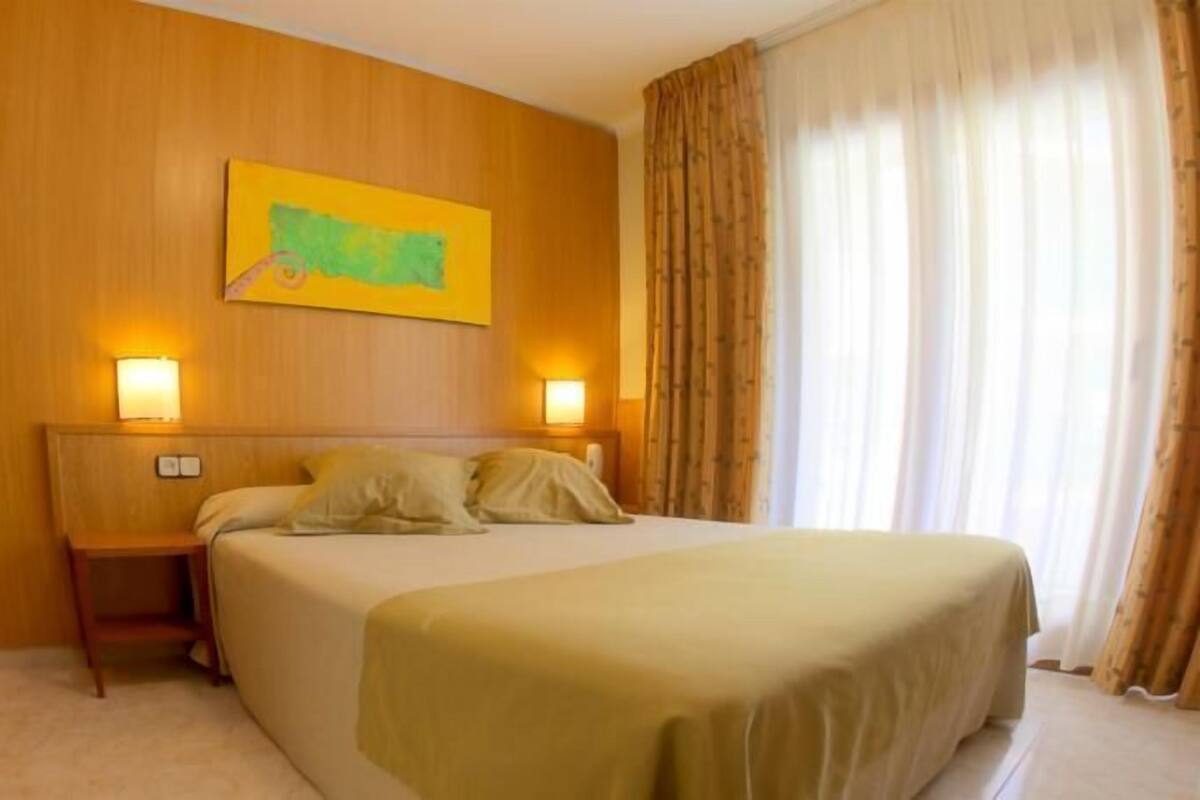 Una habitación de hotel con cama, mesitas de noche y un cuadro en la pared.