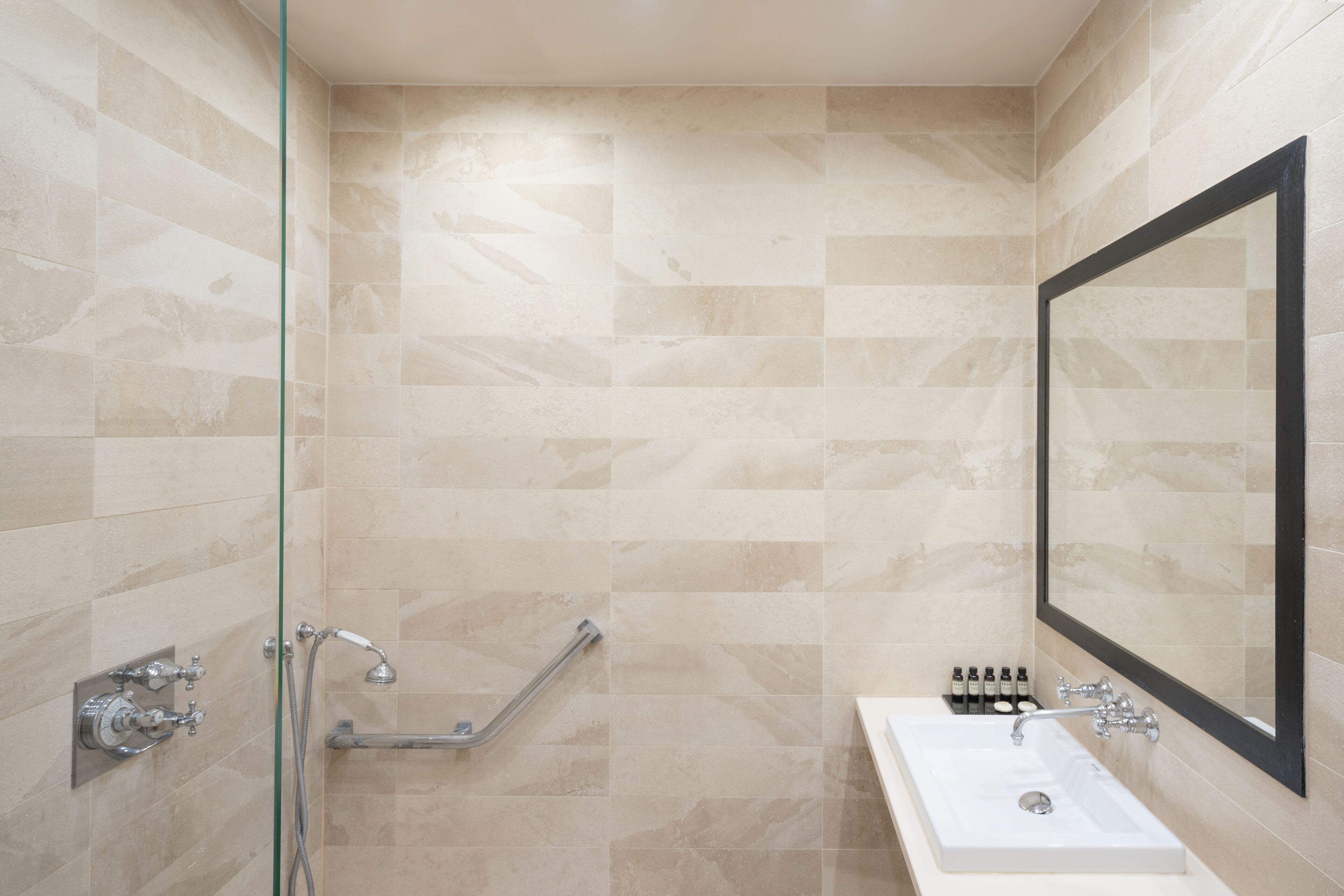 A modern bathroom with a glass shower enclosure, a white sink, and a large mirror.