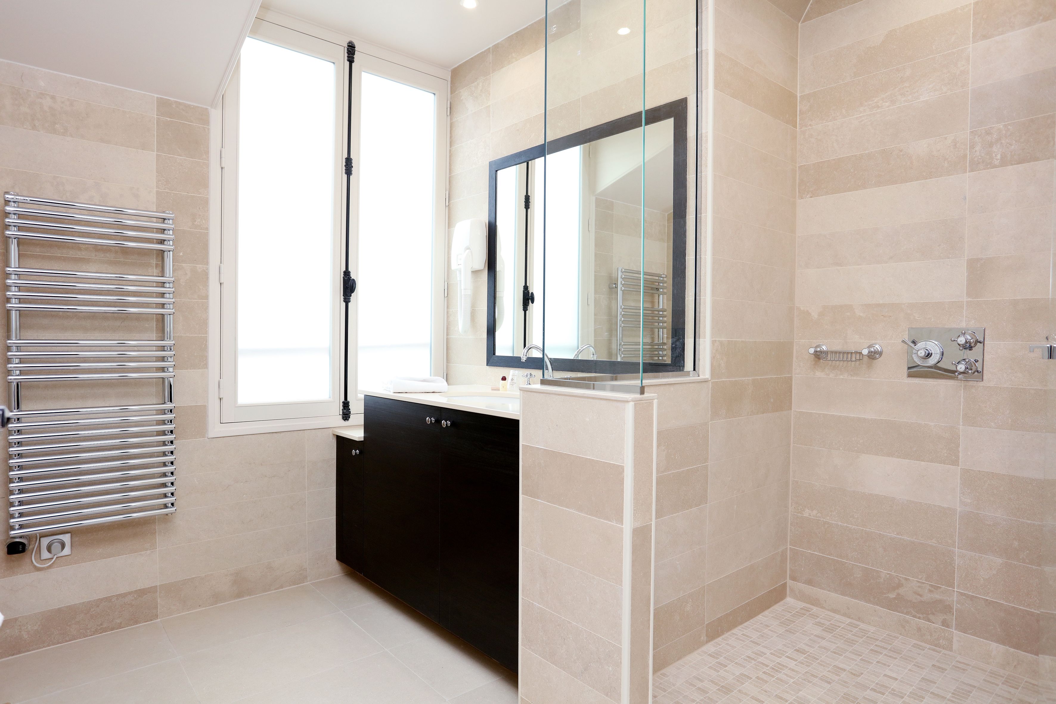 Un baño moderno con cabina de ducha de vidrio, un mueble negro y una puerta de ducha de cristal.