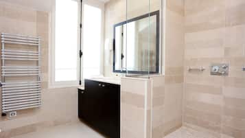 Un baño moderno con cabina de ducha de vidrio, un mueble negro y una puerta de ducha de cristal.