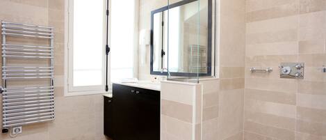 A modern bathroom with a glass shower enclosure, a black cabinet, and a glass shower door.