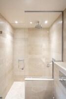 A modern bathroom with a glass-enclosed shower, a built-in sink, and a towel rack.