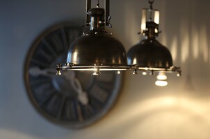 A wall-mounted clock with a round face and Roman numerals.