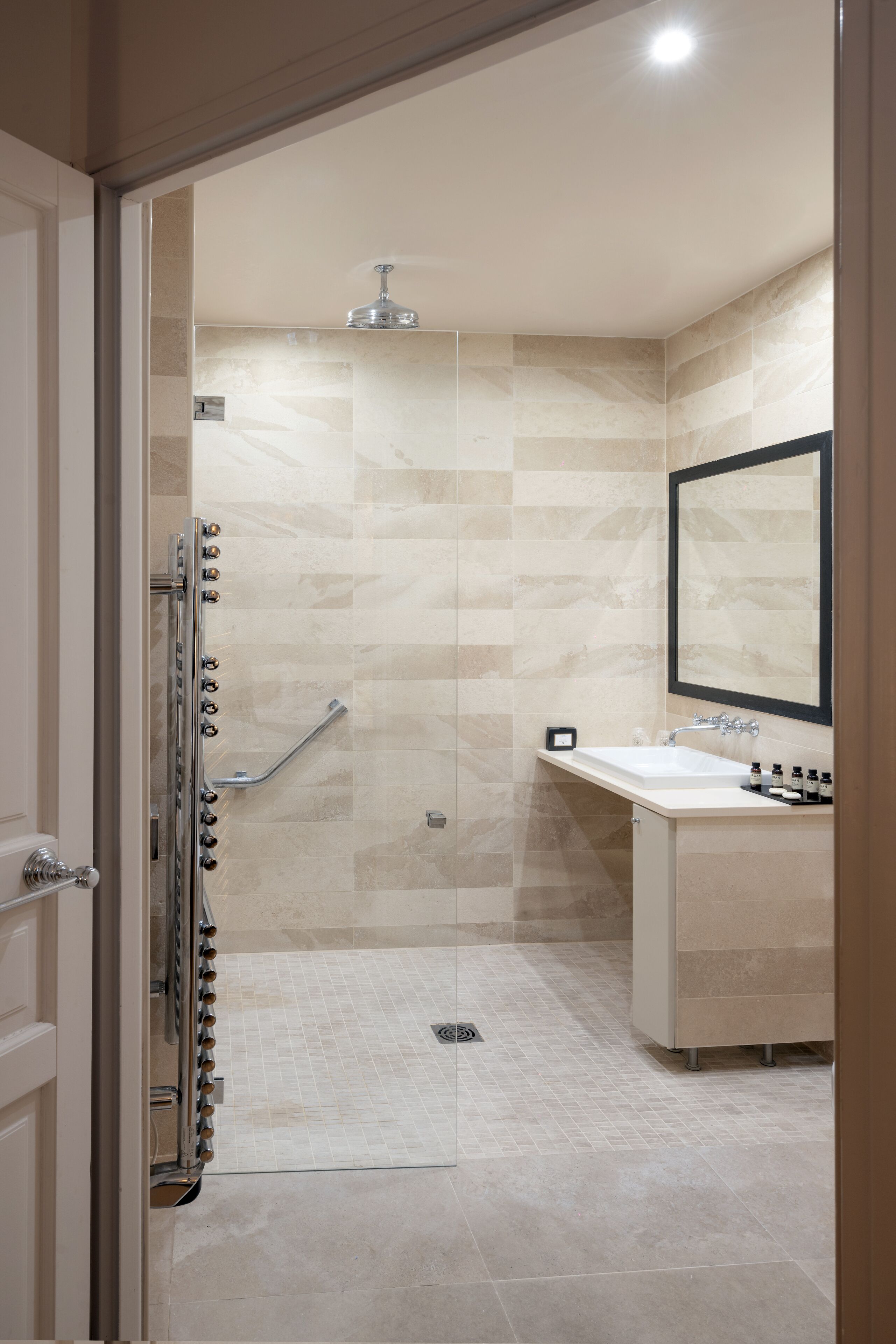 Een moderne badkamer met een douche, wastafel en spiegel.
