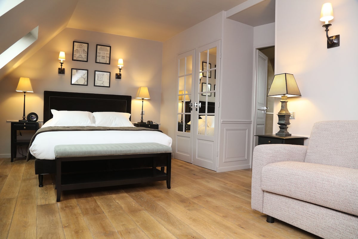 Un dormitorio con cama, mesitas de noche, un sofá y un armario.