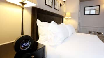 Una habitación de hotel con una cama, un reloj digital y lámparas fijadas a la pared.