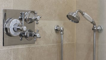 Une salle de bain équipée d’un panneau de commande de douche fixé au mur et d’un pommeau de douche à main.