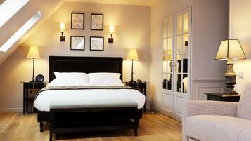 Un dormitorio ordenado con una cama grande, dos mesitas de noche con lámparas, una silla y un armario con puertas de cristal.