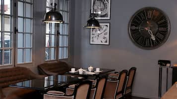 Comedor con mesa de vidrio, sillas de cuero y un reloj de pared grande.