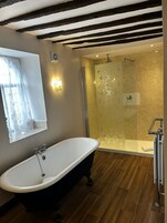 Un baño con una bañera independiente, una ducha con cerramiento de vidrio y un tocador con espejo.