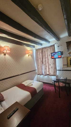 A hotel room with a bed, a desk, a chair, a TV, and a window with curtains. - The Rose and Crown Hotel (Wisbech)