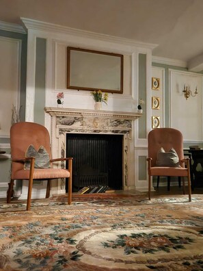 A room with a fireplace, two armchairs, a patterned rug, and wall-mounted picture frames. - The Rose and Crown Hotel (Wisbech)