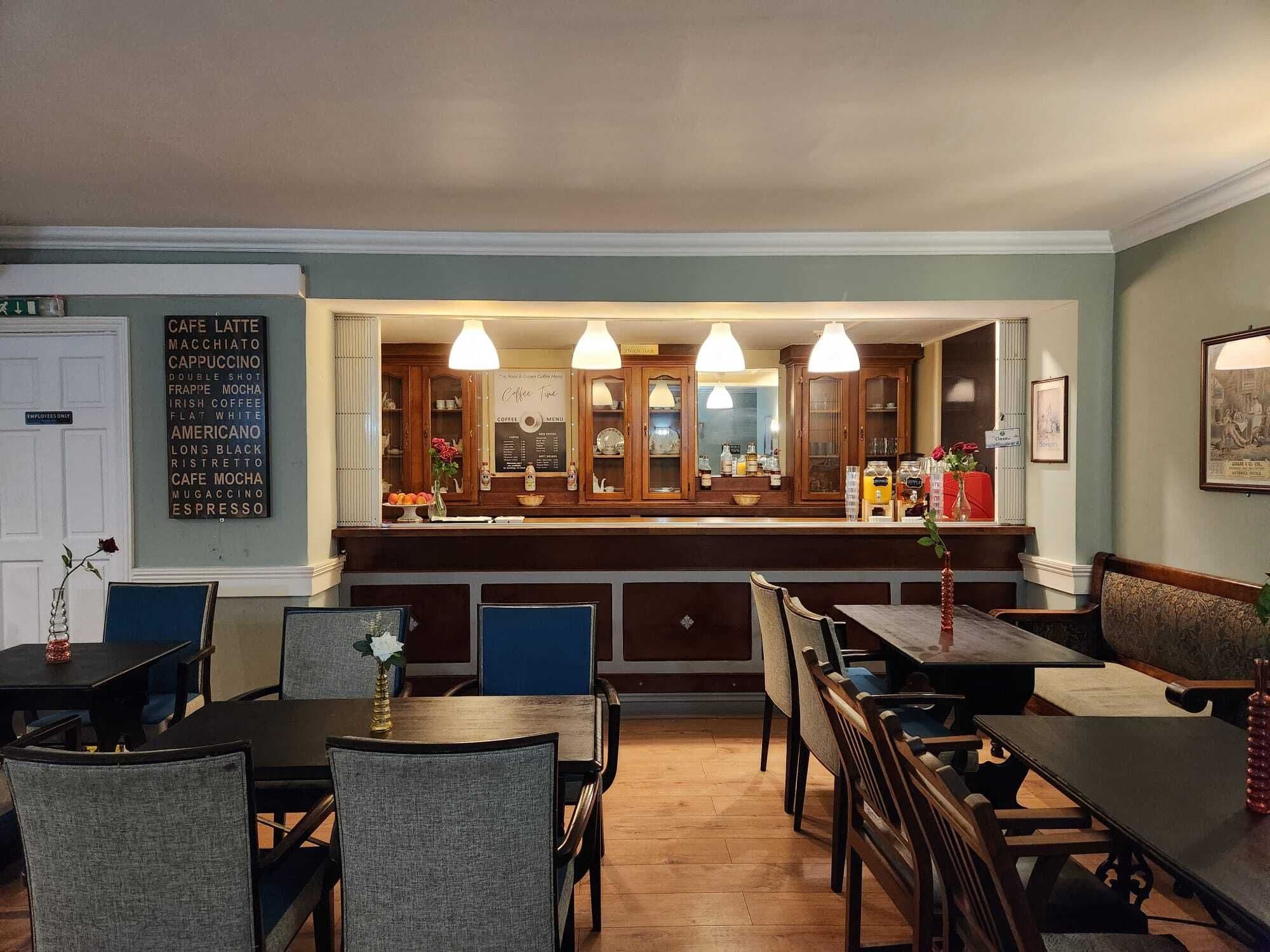 Um restaurante com área de bar, armários de madeira e um quadro de cardápio.