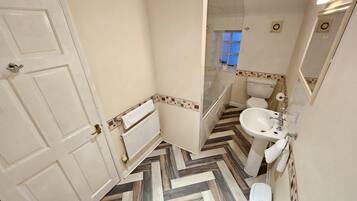 Un baño con un radiador blanco, un lavabo y un inodoro.