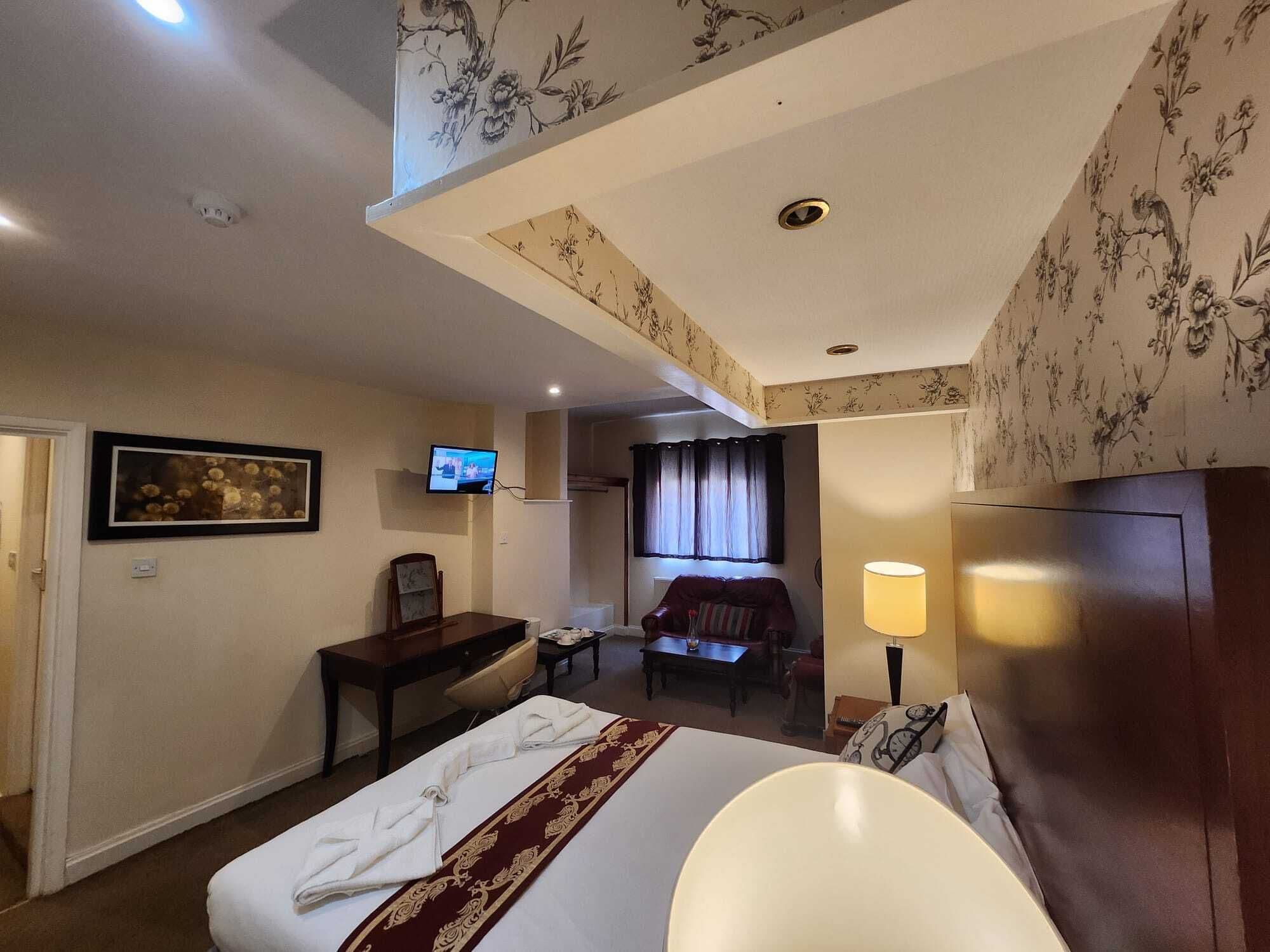 Una habitación de hotel con una cama, un escritorio, un televisor, un sofá y una lámpara.