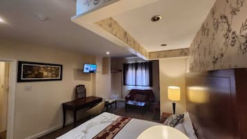 Una habitación de hotel con una cama, un escritorio, un televisor, un sofá y una lámpara.