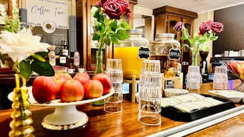 Zona de cafetería con menú, exhibición de fruta y dispensadores de bebidas.