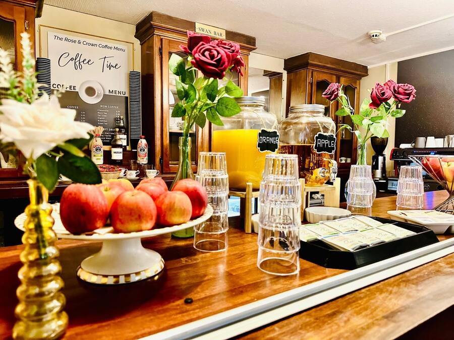 Zona de cafetería con menú, exhibición de fruta y dispensadores de bebidas.