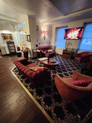 A living room with a fireplace, a television, and a large window. - The Rose and Crown Hotel (Wisbech)