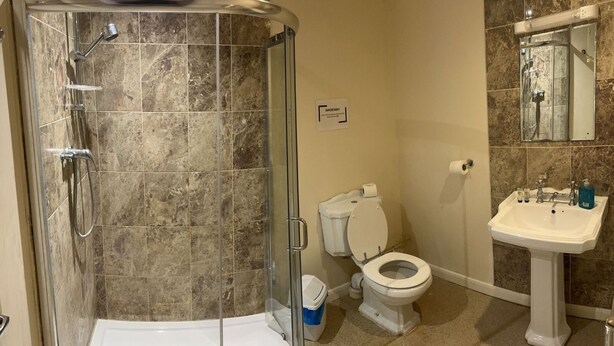 A bathroom with a glass-enclosed shower, a toilet, and a sink. - The Rose and Crown Hotel (Wisbech)