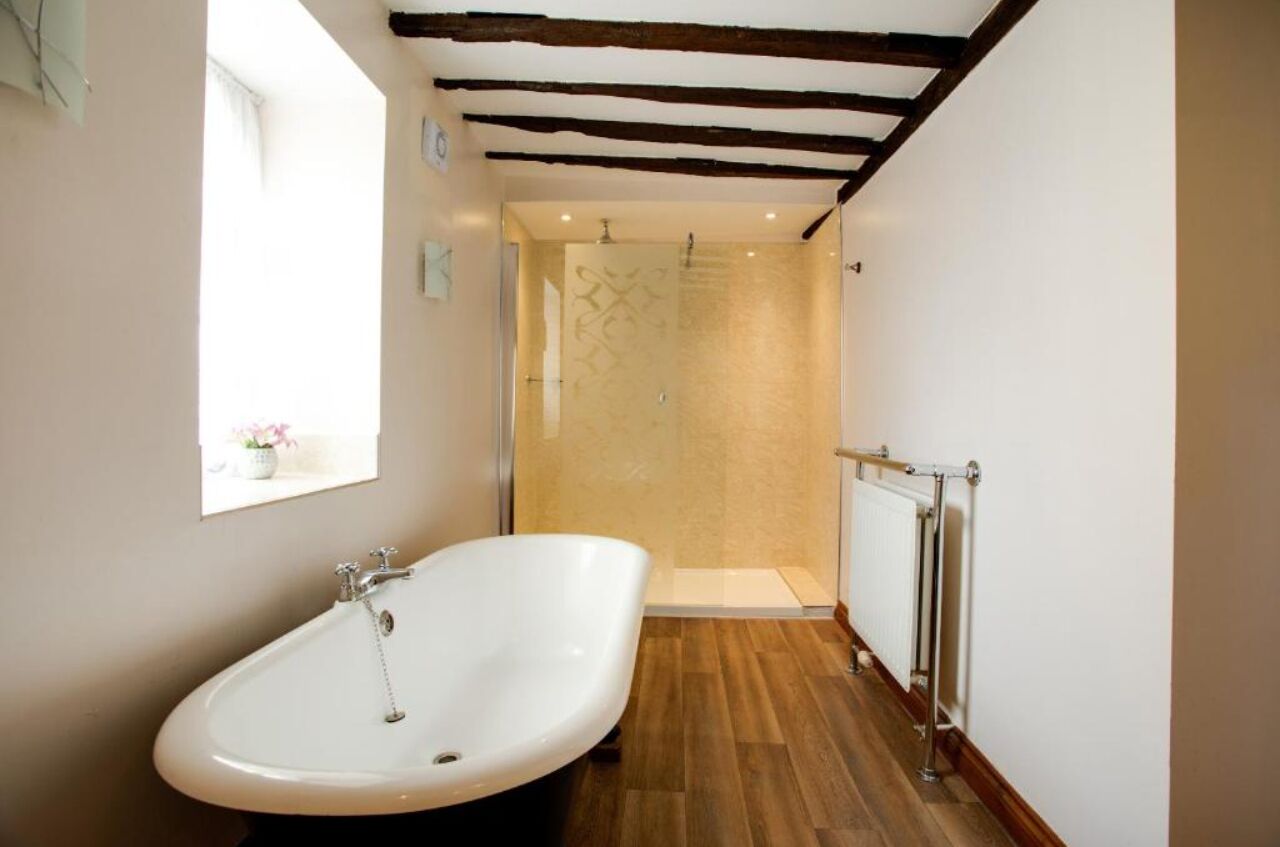 A bathroom with a freestanding bathtub, a glass shower enclosure, and a radiator.