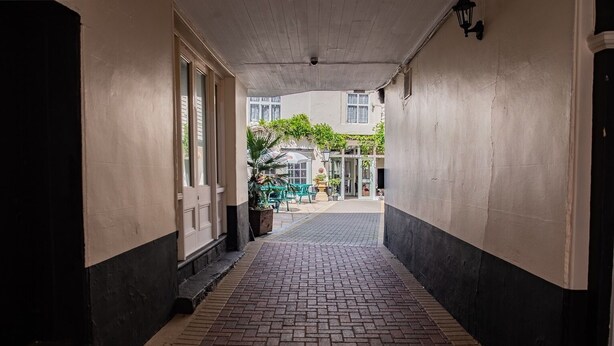 A corridor with a brick floor leading to a building entrance. - The Rose and Crown Hotel (Wisbech)