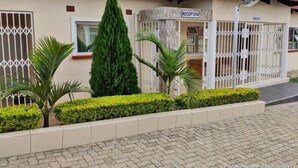 A building with a reception area, a red roof, and a gated entrance. - Home Up Guest House (Blantyre)
