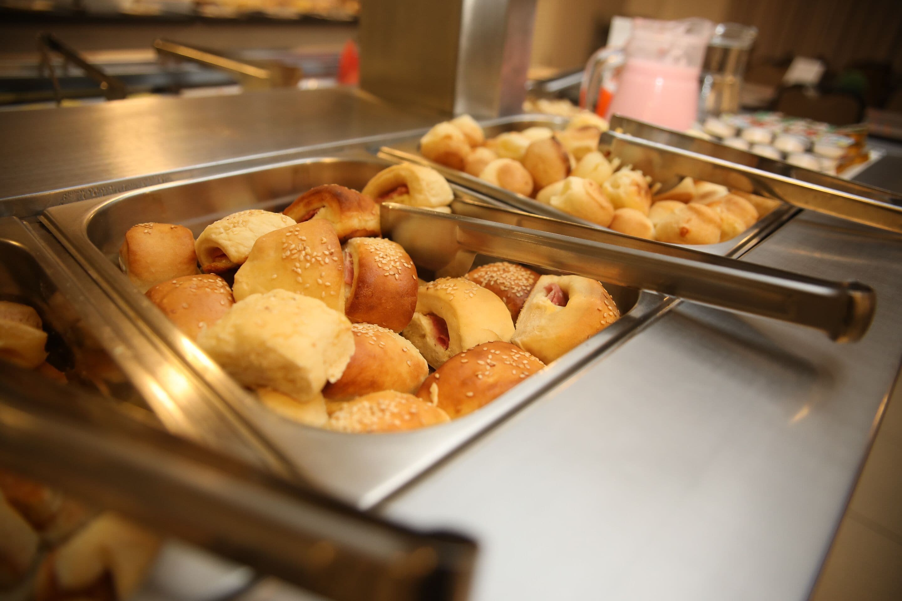 A buffet with various baked goods and a beverage dispenser.