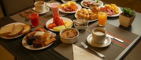 A breakfast buffet with various dishes, including bread, fruits, and beverages.