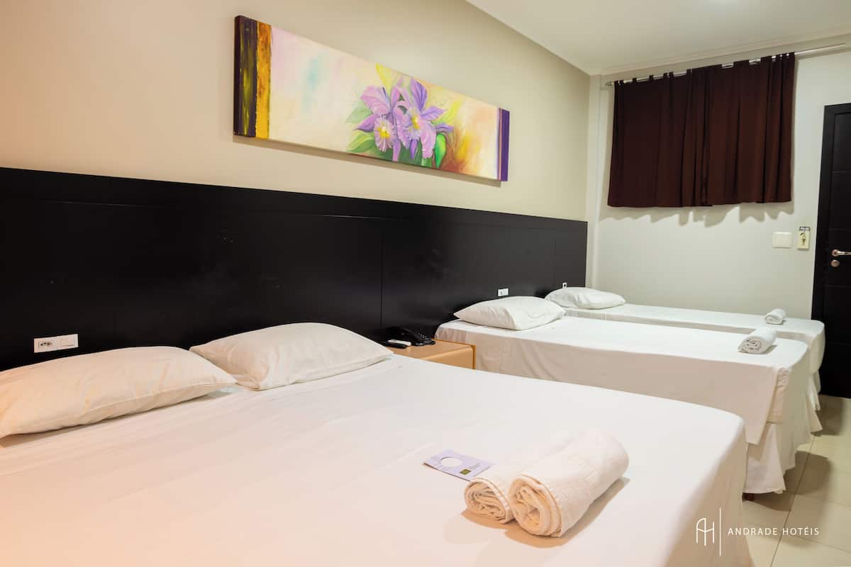 A hotel room with two beds, a painting on the wall, a nightstand with a phone, and a door with a curtain.