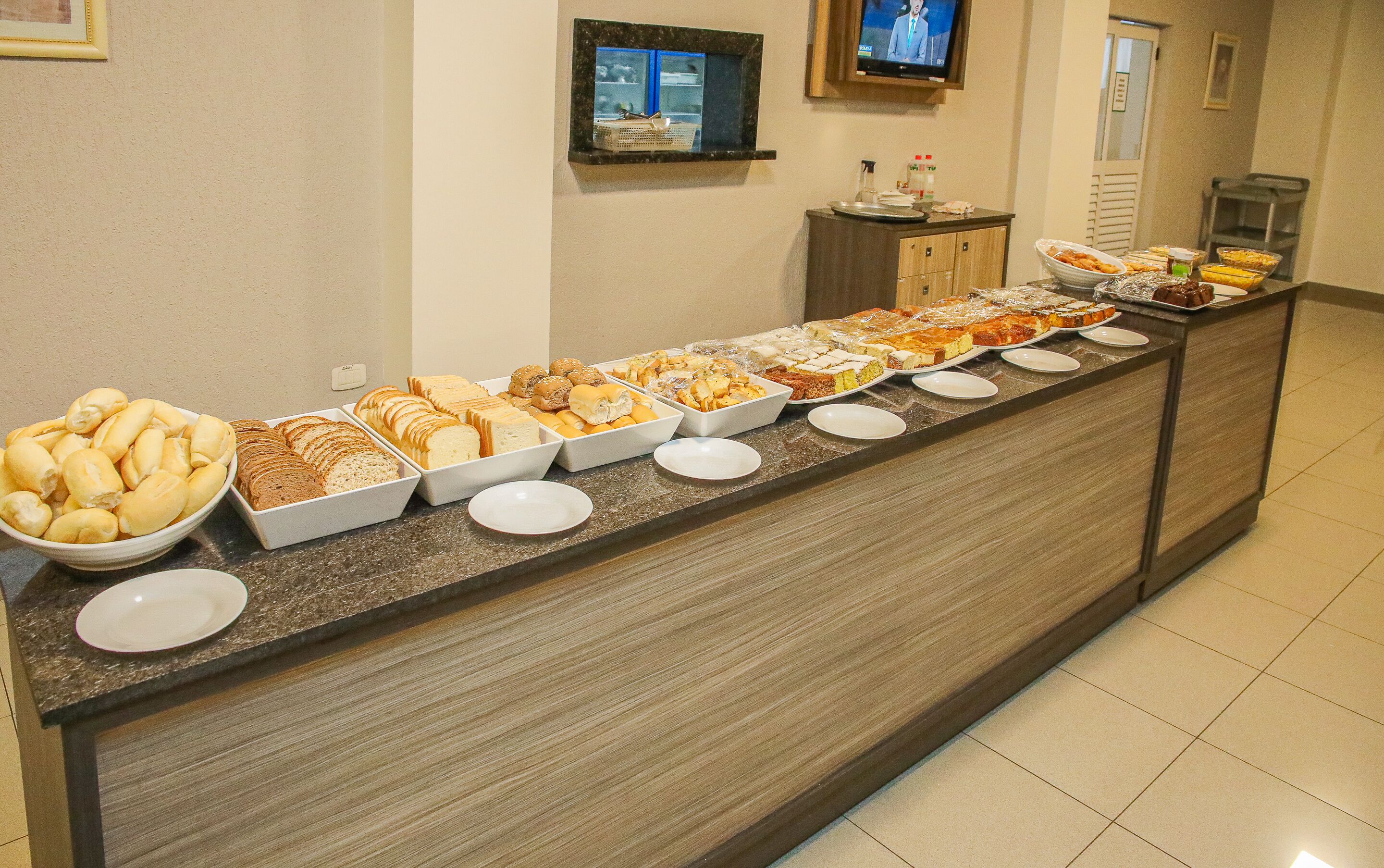 A buffet counter with various food items and a television screen in the background.
