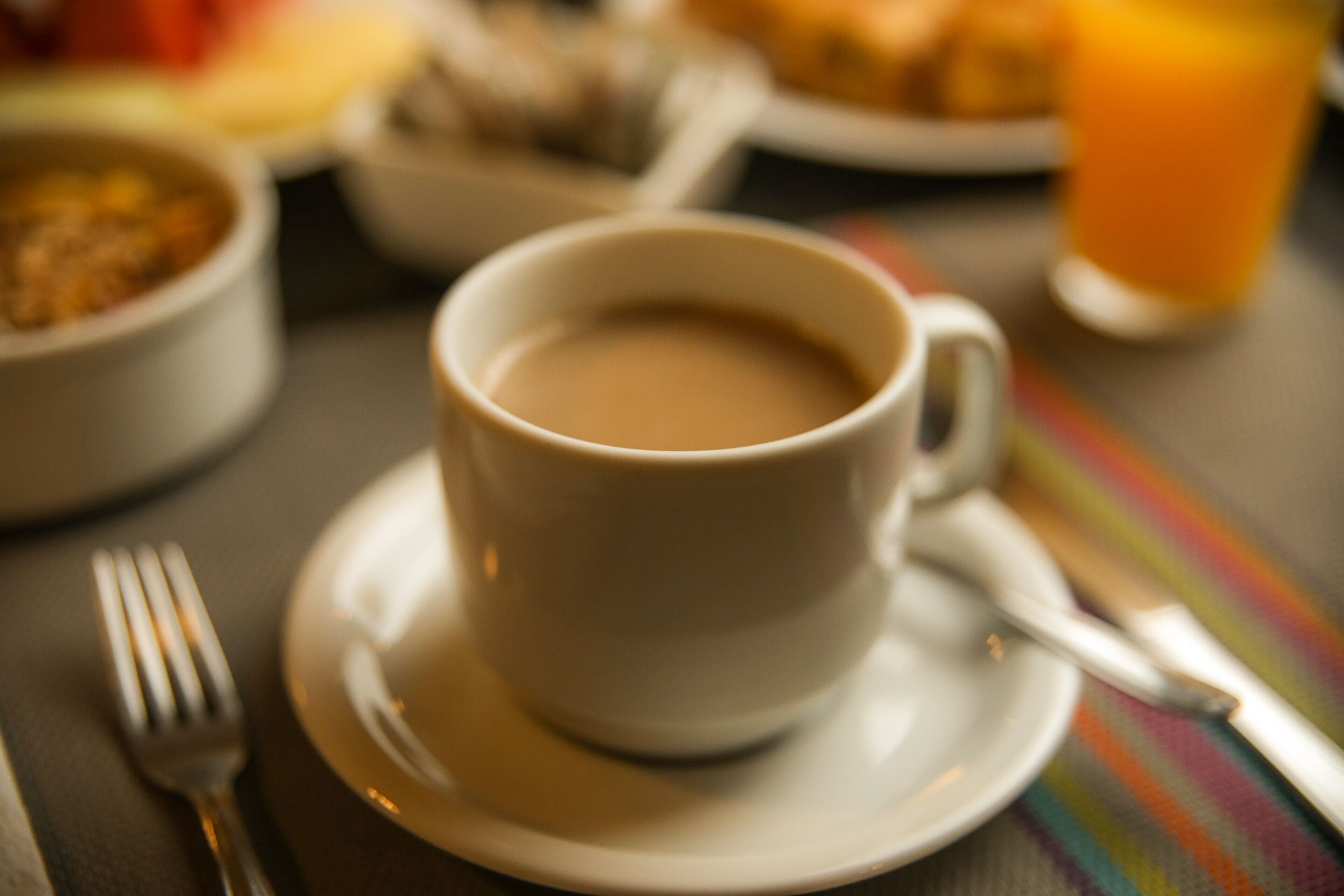 Une tasse de café posée sur une soucoupe, avec une fourchette à côté.
