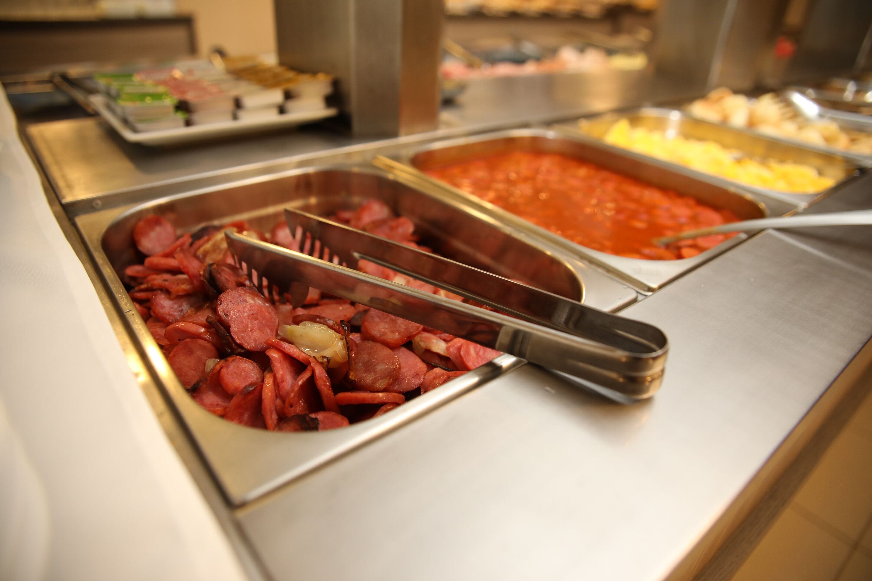 Un bufé con diversas opciones de comida, incluyendo carnes en rodajas y platos de pasta.