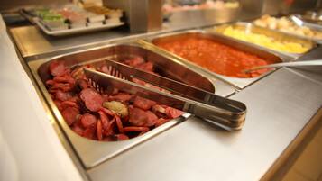 Un bufé con diversas opciones de comida, incluyendo carnes en rodajas y platos de pasta.