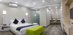 A modern hotel room with a large bed, a desk, and a wardrobe. - Fallsway Suites (Lusaka)