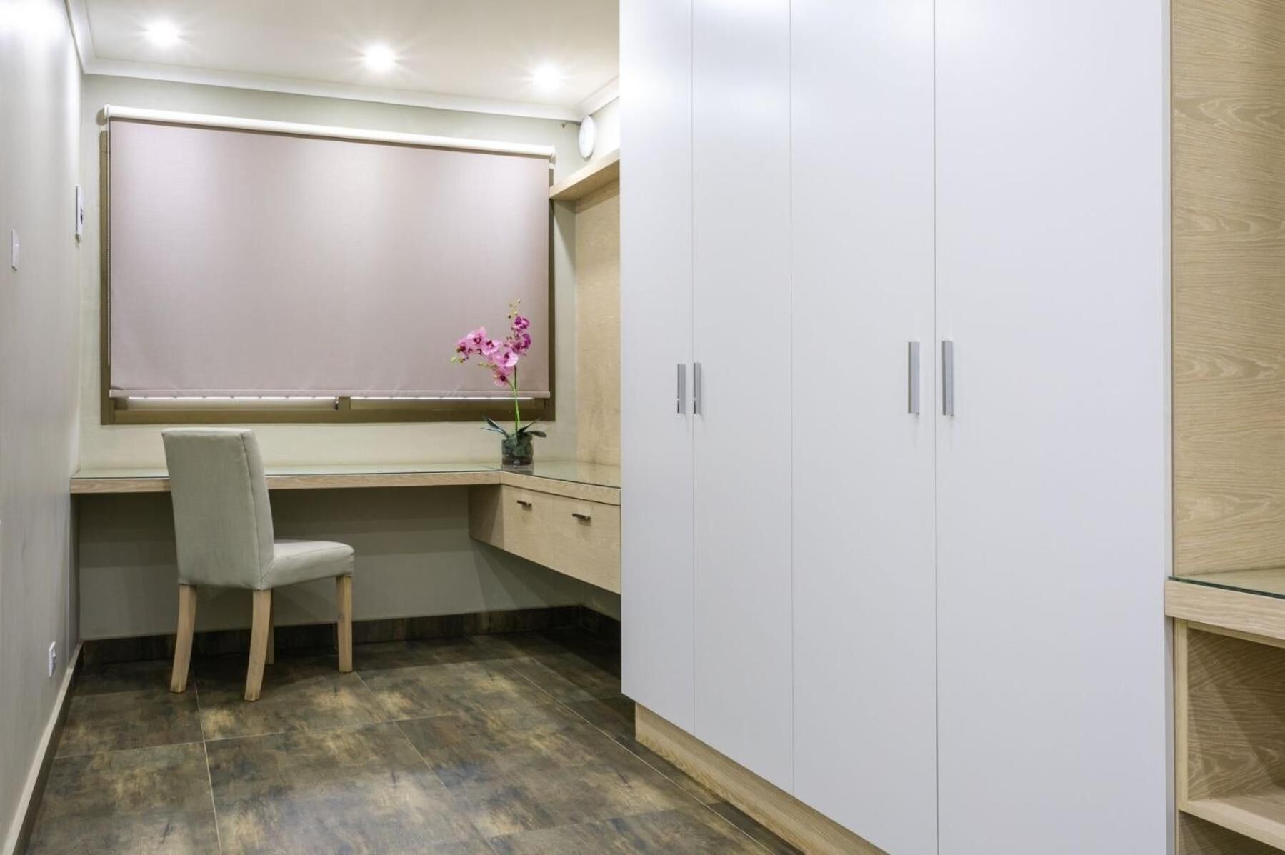 Een studeerkamer met een bureau, stoel en garderobe.