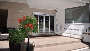 Ein Hotel mit Eingangsbereich, einer Rezeption und einem Glastür-Eingang. Auf dem Schild steht 'Miramare hotel'.