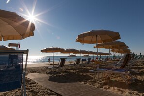 A beach with rows of sun umbrellas and lounge chairs.