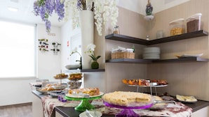 Ein reichhaltiges Buffet mit verschiedenen Speisen, darunter Kuchen und Gebäck, sowie eine dekorative Orchideenanordnung.