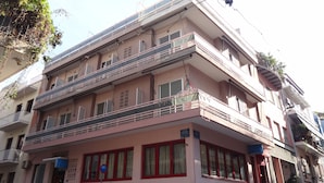 Un edificio de varios pisos con balcones, un letrero que indica un hotel, y un coche estacionado frente a él.
