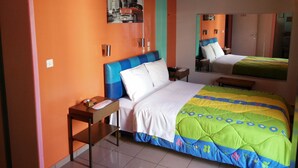 Una habitación de hotel con cama, mesita de noche, espejo y una pared decorada con un mural.