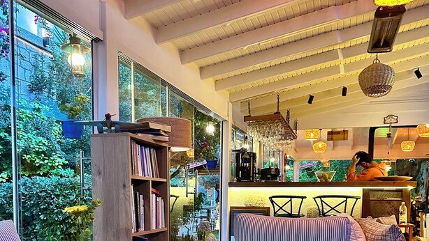 A cozy living room with a sofa, armchair, and coffee table, a bookshelf, and a view of the outdoors. - Kayezta Hotel Alacati (Cesme)