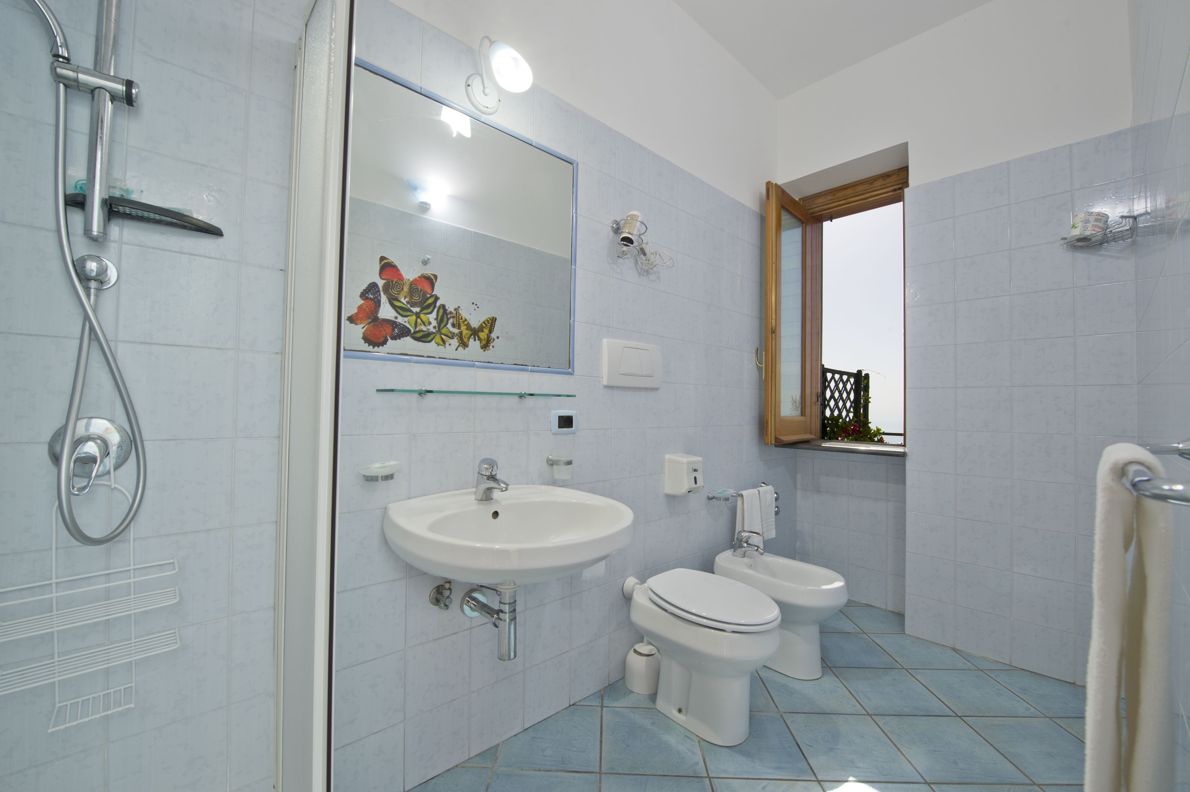 A bathroom with a shower, two toilets, a sink, and a mirror.