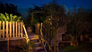 Un jardin agrémenté d’une terrasse en bois, de marches en pierre et de différentes espèces de plantes.