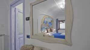 A bedroom with a large mirror reflecting a bed, a window, and a view of a bridge. - La Mela Blu (Furore)