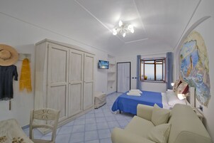 Un dormitorio con cama, sofá, armario, televisión y ventana con vistas.