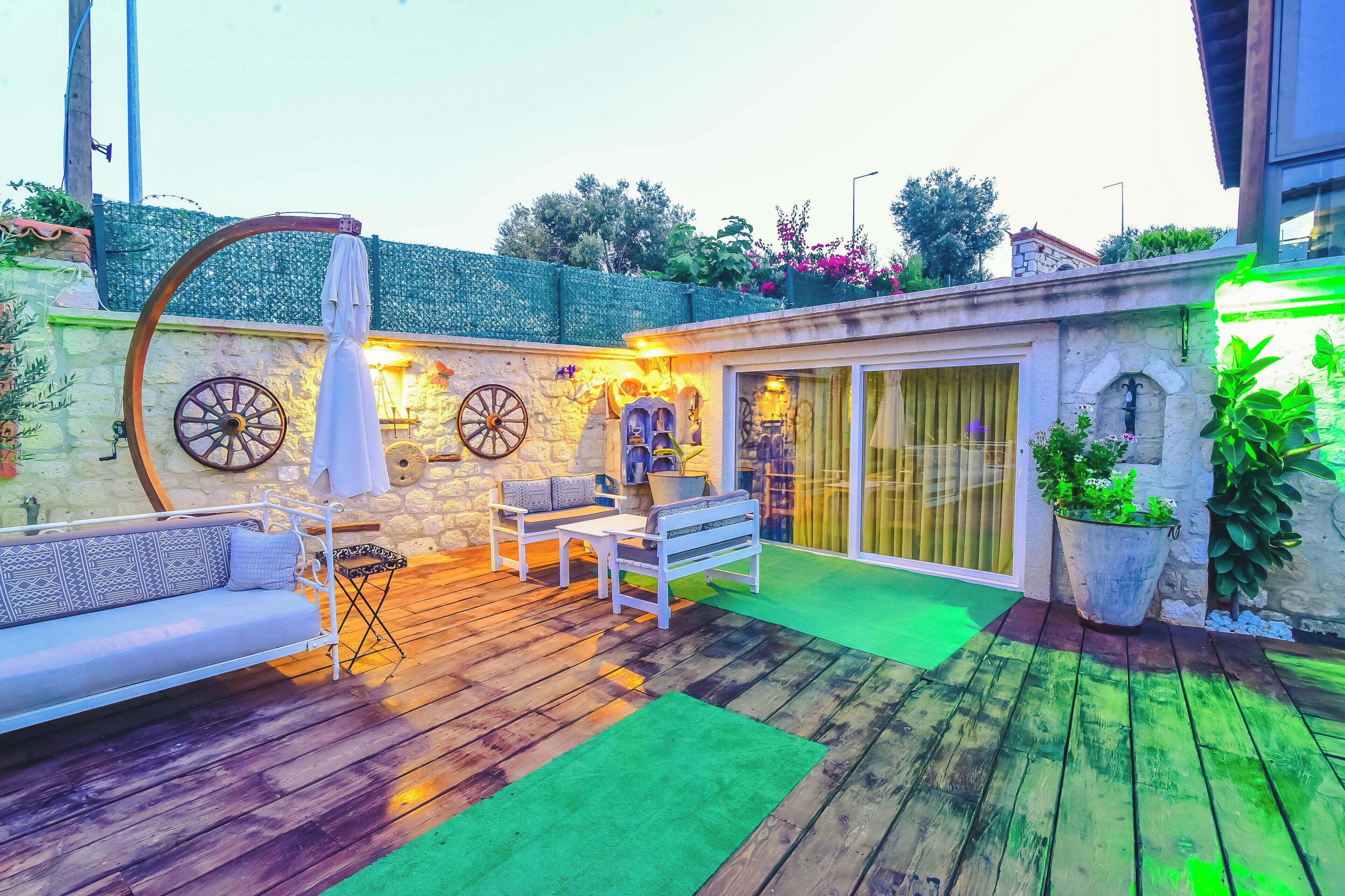 A patio with a wooden deck, a white sofa, and a table with chairs.