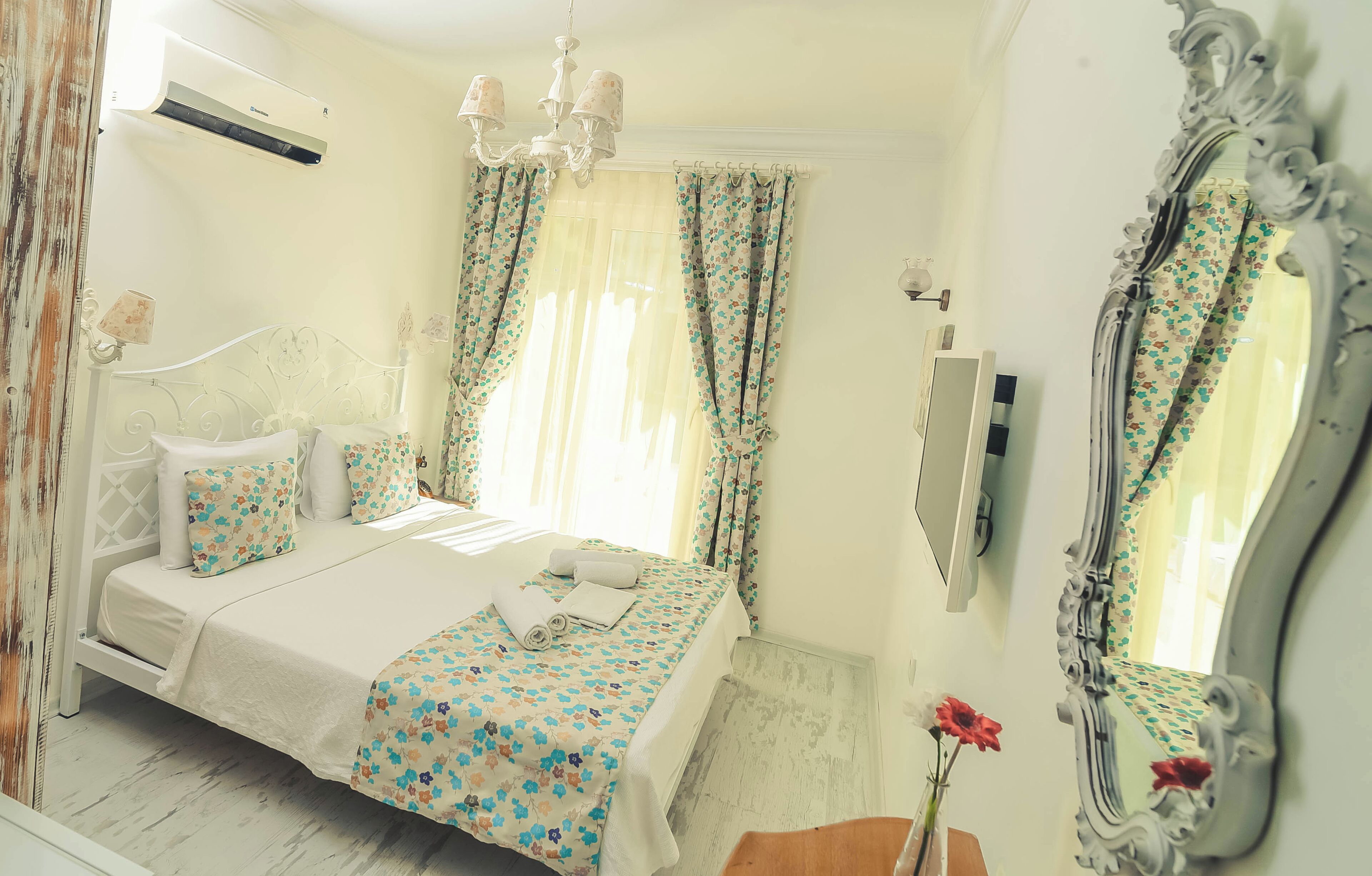 Un dormitorio con cama, cortinas, espejo y candelabro.